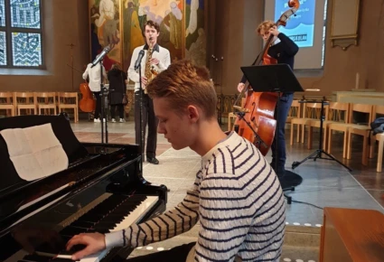 Kille sitter i kyrkan och spelar piano.