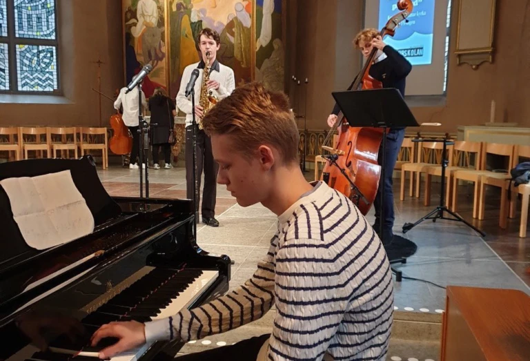 Kille sitter i kyrkan och spelar piano.