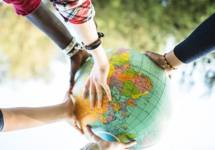 Ungdomar med olika bakgrund lyfter en jordglob tillsammans.