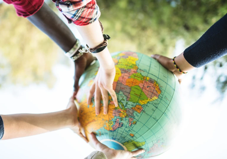 Ungdomar med olika bakgrund lyfter en jordglob tillsammans.