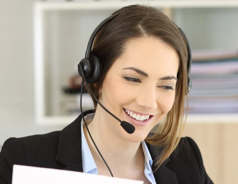 Tjej som pratar i ett headset och tittar i sin dator.