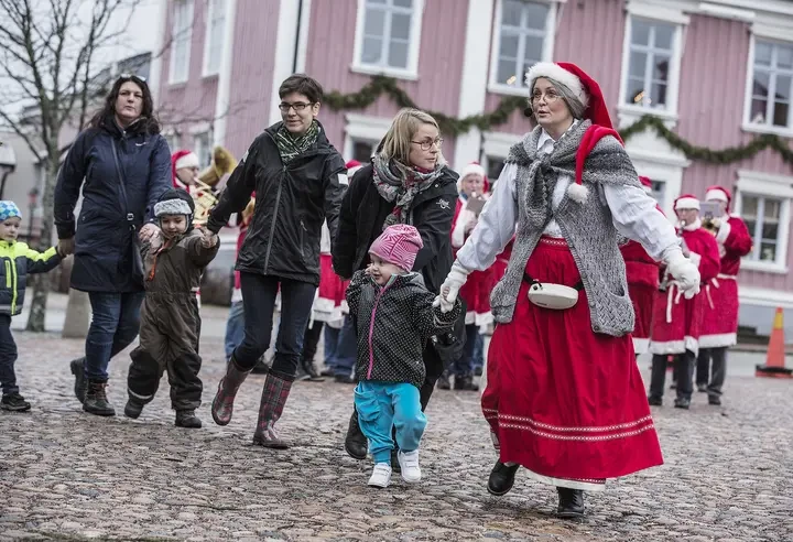 Barn och vuxna dansar kring granen.