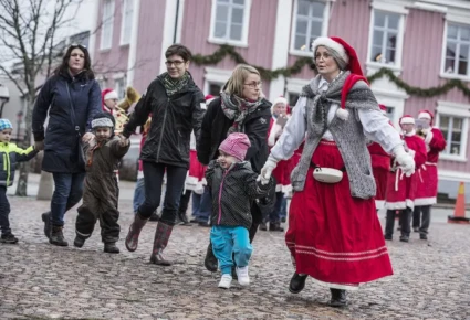 Barn och vuxna dansar kring granen.