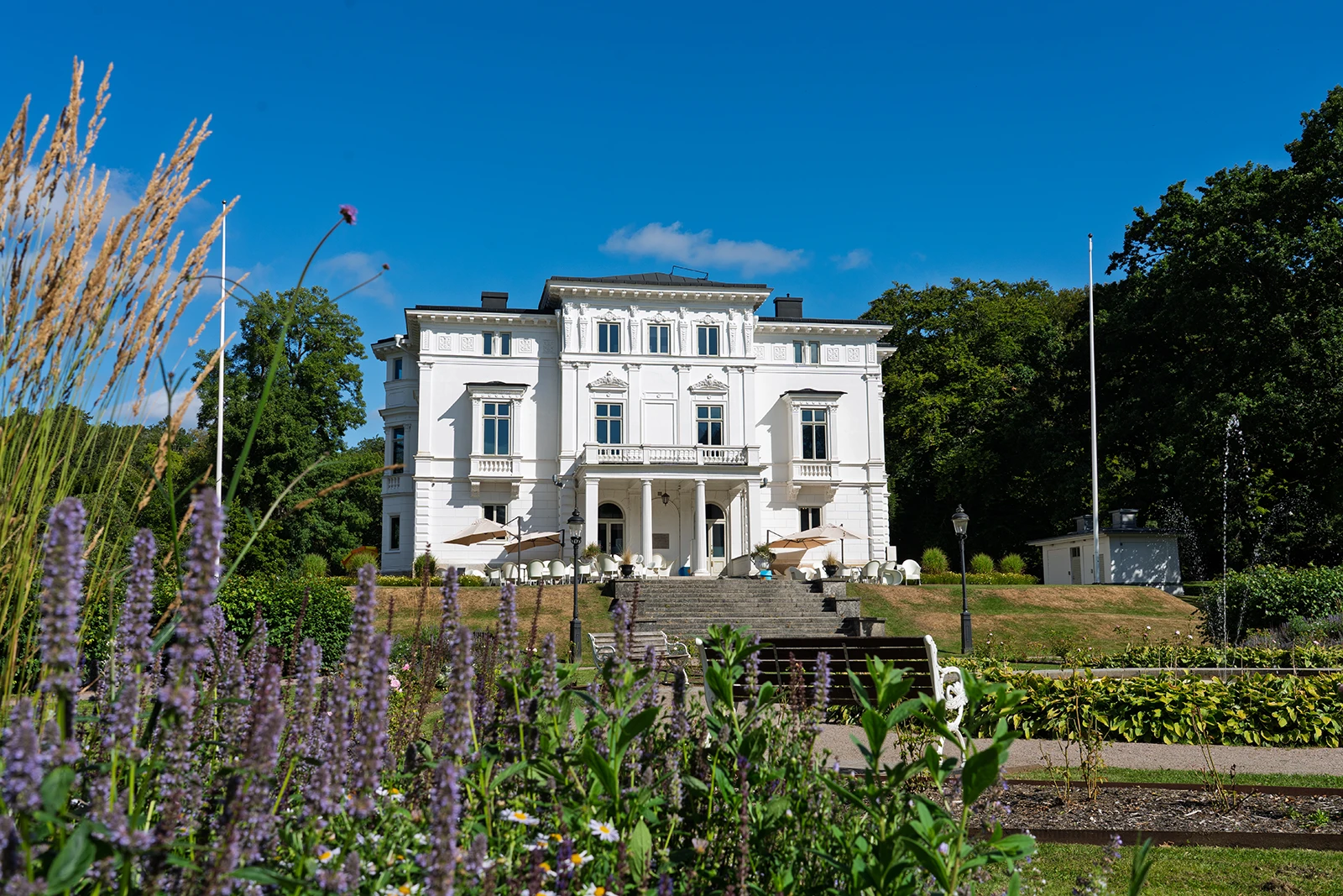Vit slottsliknande byggnad i gröna omgivningar.
