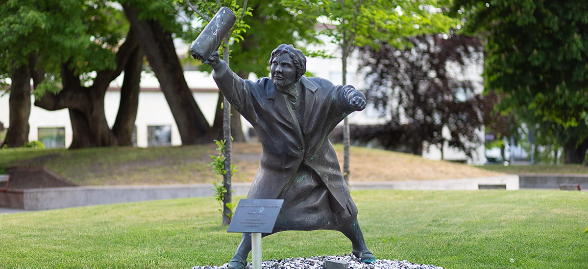 Fotografi av konstverket "Med handväskan som vapan". Föreställer en kvinna som höjer en väska upp i luften.