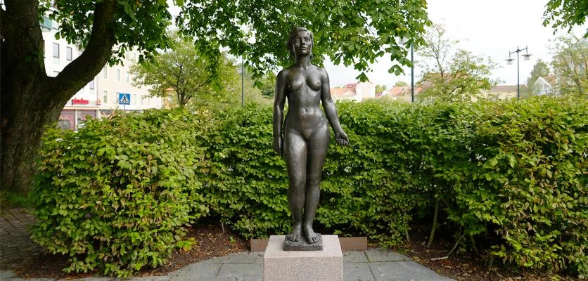 En staty av en kvinna i en park på sommaren.