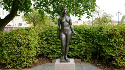 En staty av en kvinna i en park på sommaren.