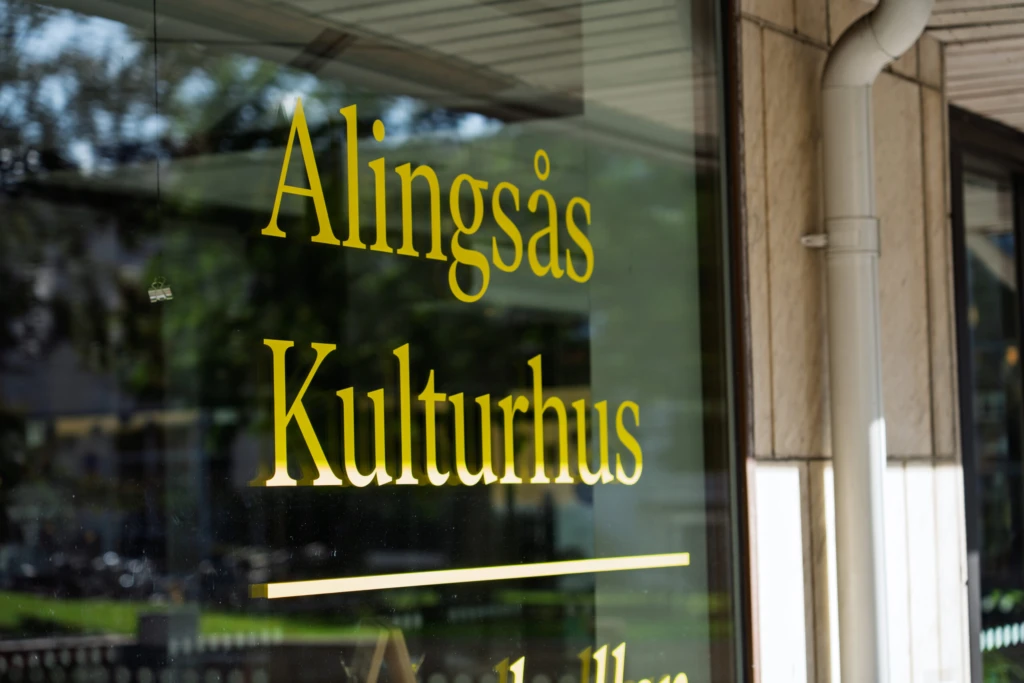 Det står Alingsås Kulturhus på ett fönster. Texten är gul