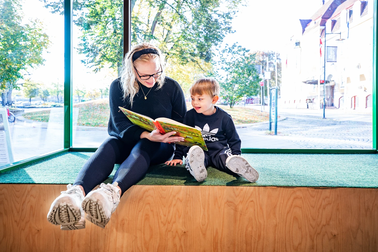 Mamma och barn läser bok på biblioteket.