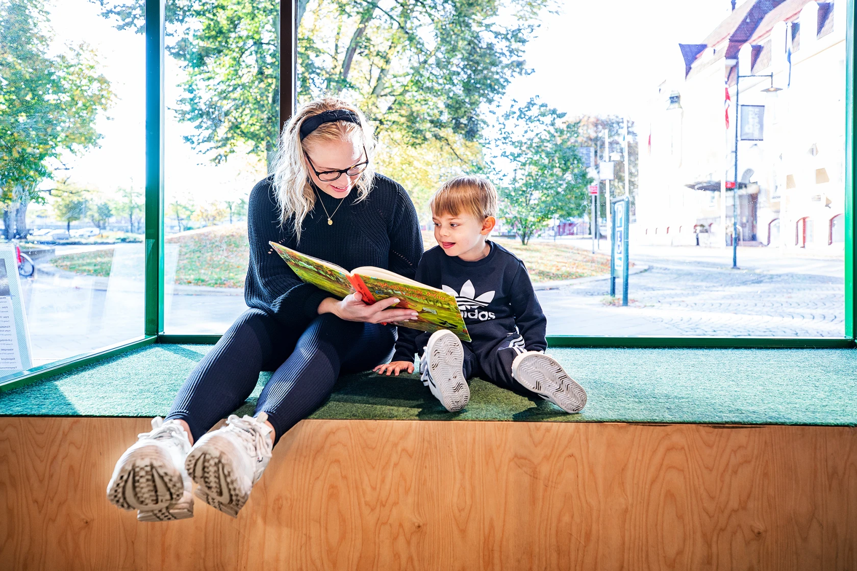 Mamma och barn läser bok på biblioteket.