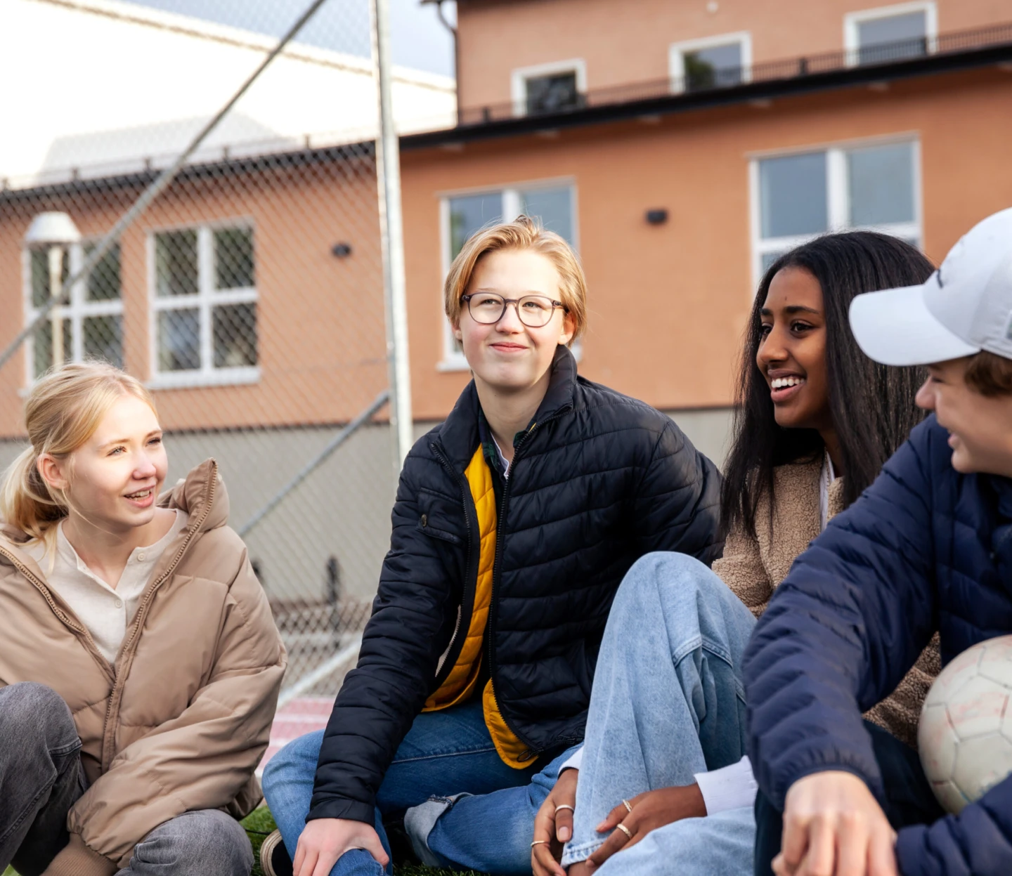 Fyra ungdomar som sitter på en skolgård.