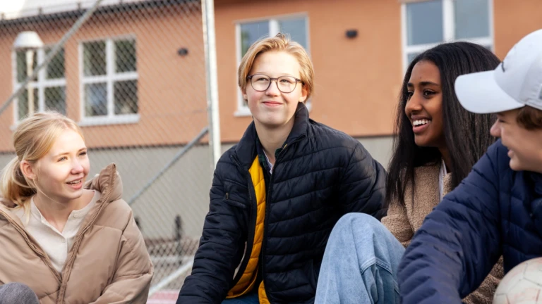 Fyra ungdomar som sitter på en skolgård.