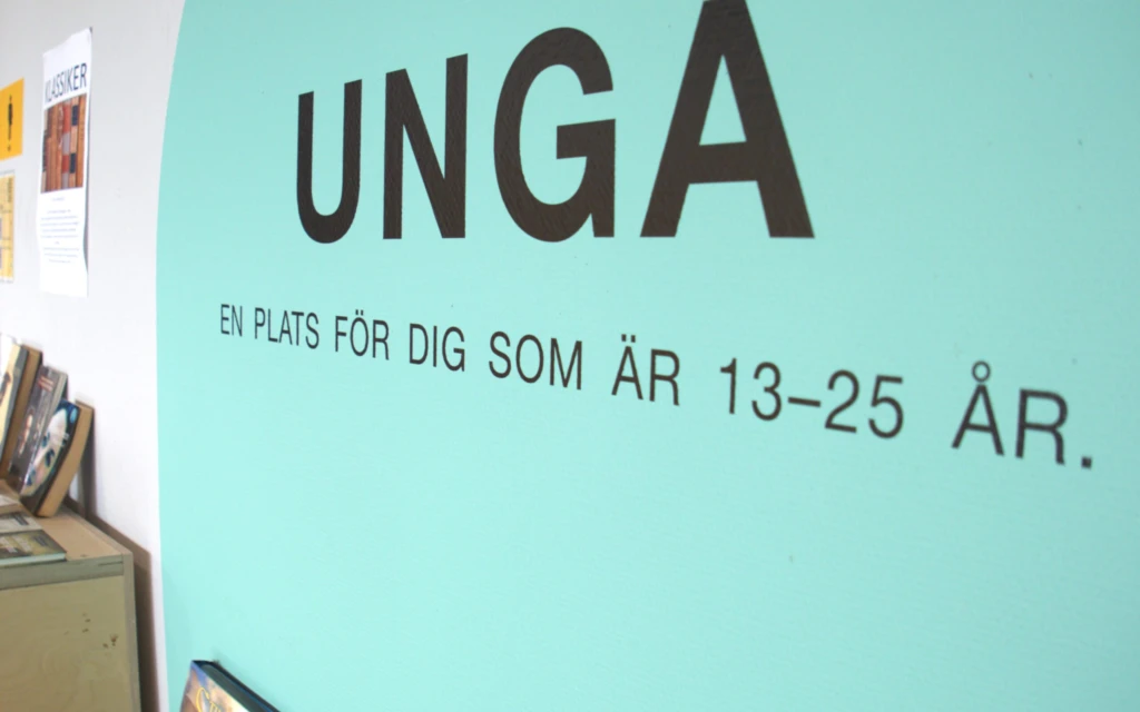 Texten "unga" på en vägg med blå bakgrund.