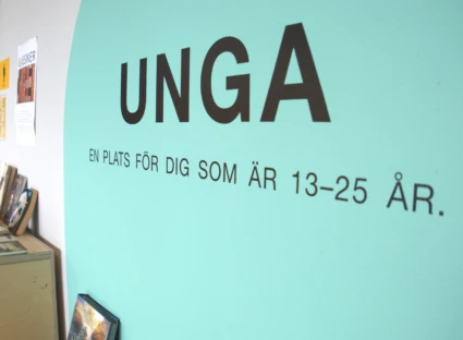 Texten "unga" på en vägg med blå bakgrund.