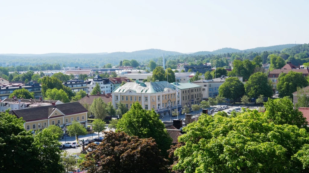 Stadskärnan i Alingsås tagen från hög höjd. Träd i förgrunden och byggnader i bakgrunden.