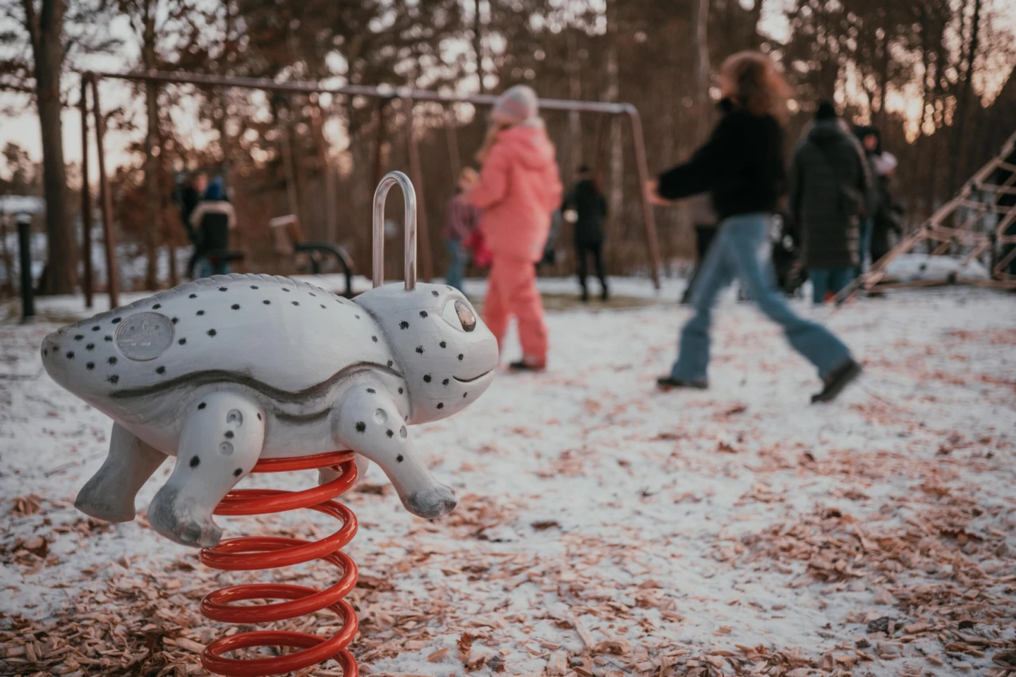 Grodattraktion på lekplats med barn i bakgrunden.