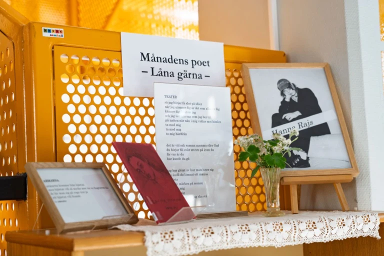 En miljöbild inne på Alingsås Kulturhus. Foto i ram, växt, böcker står på en hylla