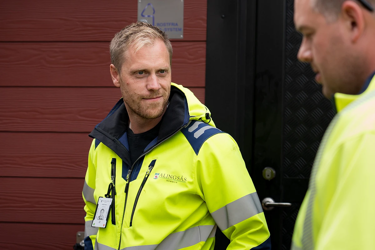 Två personer i gula kommunjackor diskuterar med varandra.