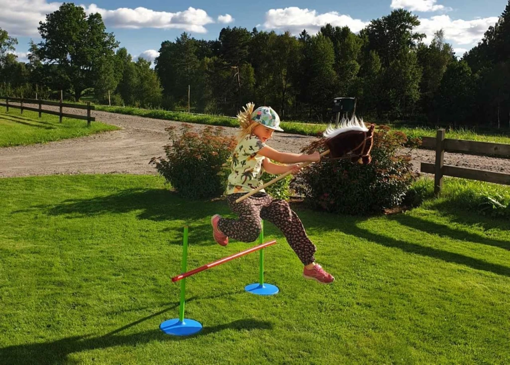 ett barn hoppar med en käpphäst