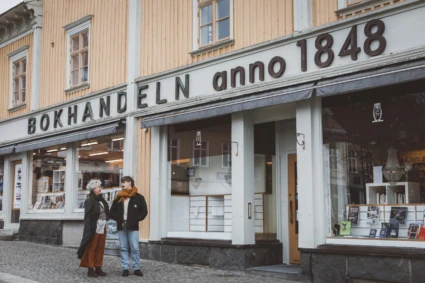Två personer står och pratar utanför bokhandeln vid Stora Torget i Alingsås.