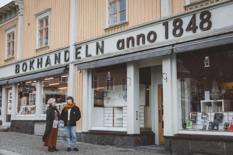 Två personer står och pratar utanför bokhandeln vid Stora Torget i Alingsås.