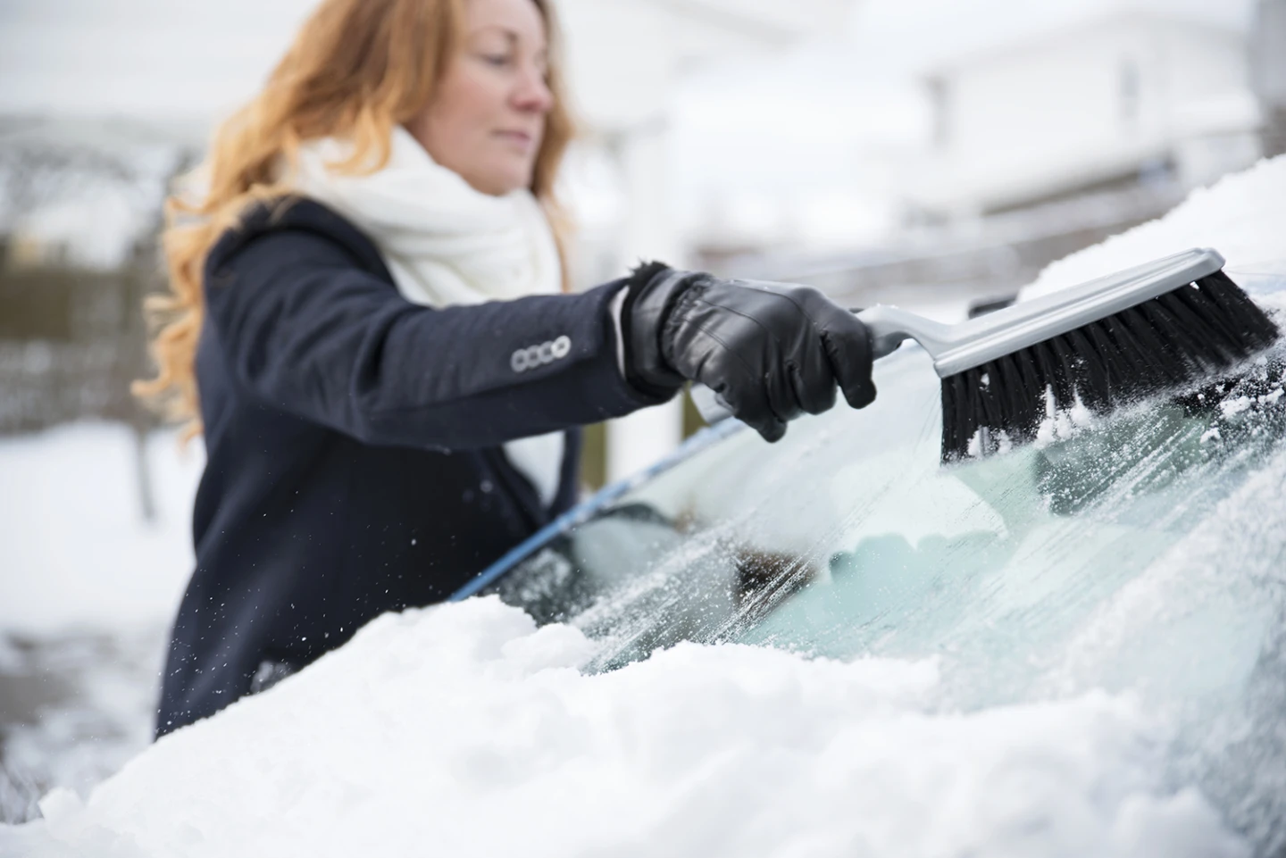 En kvinna som sopar av snön från sin bil.