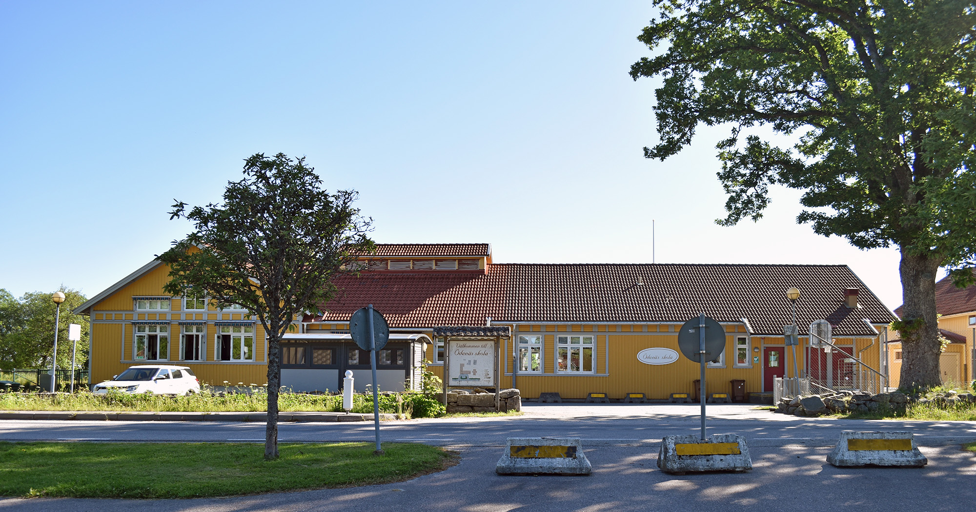 Gul skolbyggnad i bakgrund. 