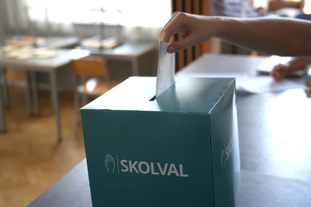 Hand stoppar ner kuvert i skolvalslåda.