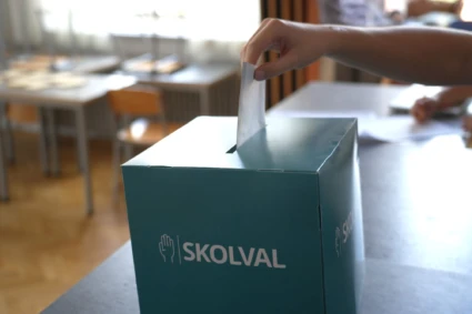 Hand stoppar ner kuvert i skolvalslåda.
