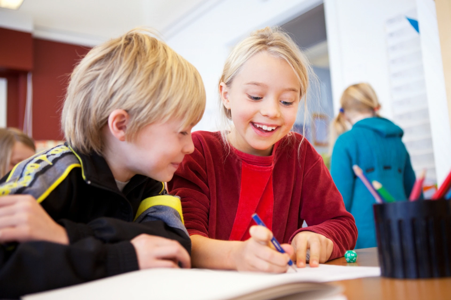Två elever sitter vid bord i skola.