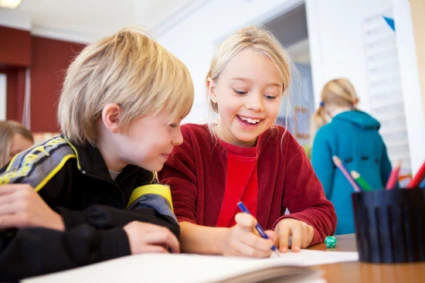 Två elever sitter vid bord i skola.