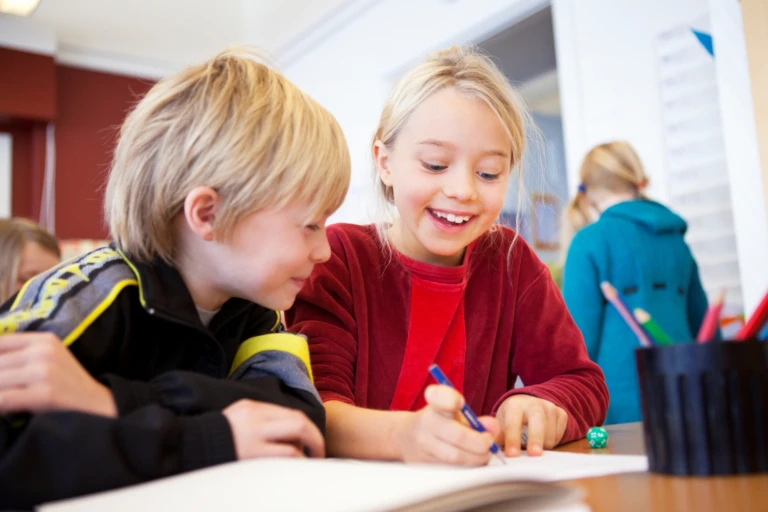 Två elever sitter vid bord i skola.